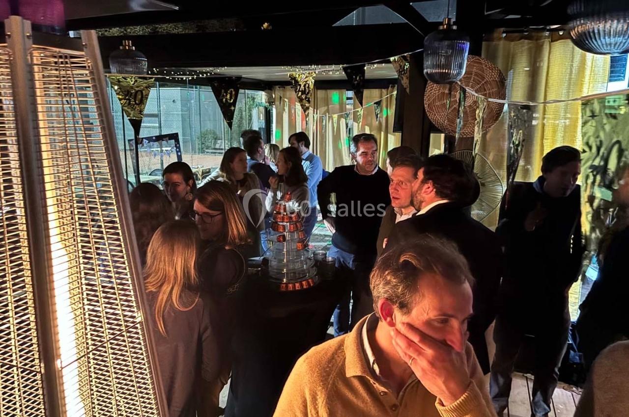 Groupe de personnes discutant dans un espace intérieur décoré, éclairé par des lampes et un chauffage d'appoint.