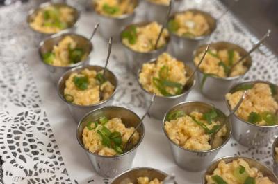 Entrée d'un café avec une terrasse équipée d'un parasol orange et des fauteuils en osier, sous un ciel ensoleillé.