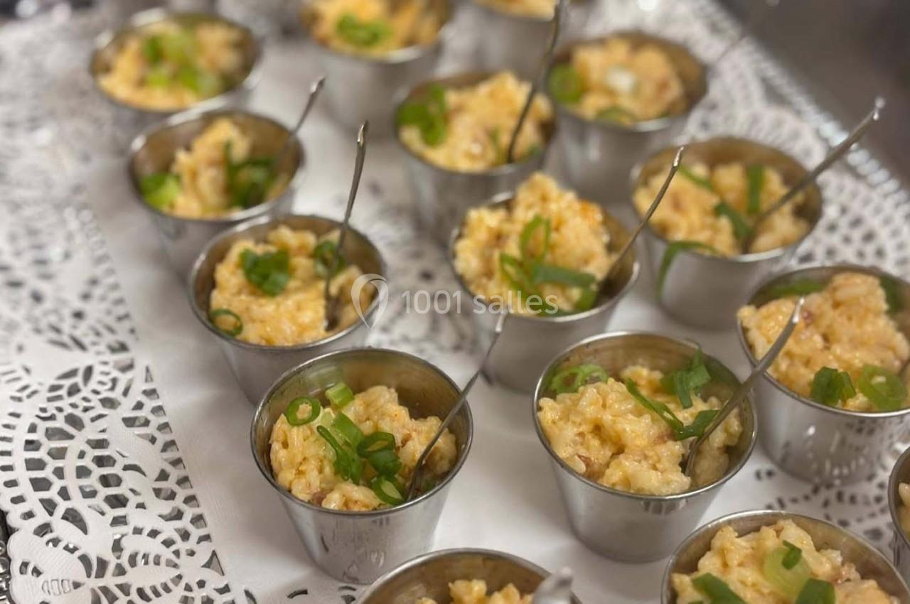 Petits ramequins en métal contenant du risotto crémeux, garnis de ciboulette, disposés sur un napperon blanc.