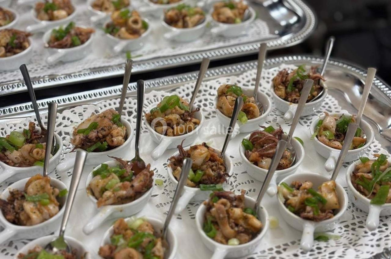 Petites coupelles de fruits de mer assaisonnés, garnies de ciboulette, présentées sur un plateau argenté.