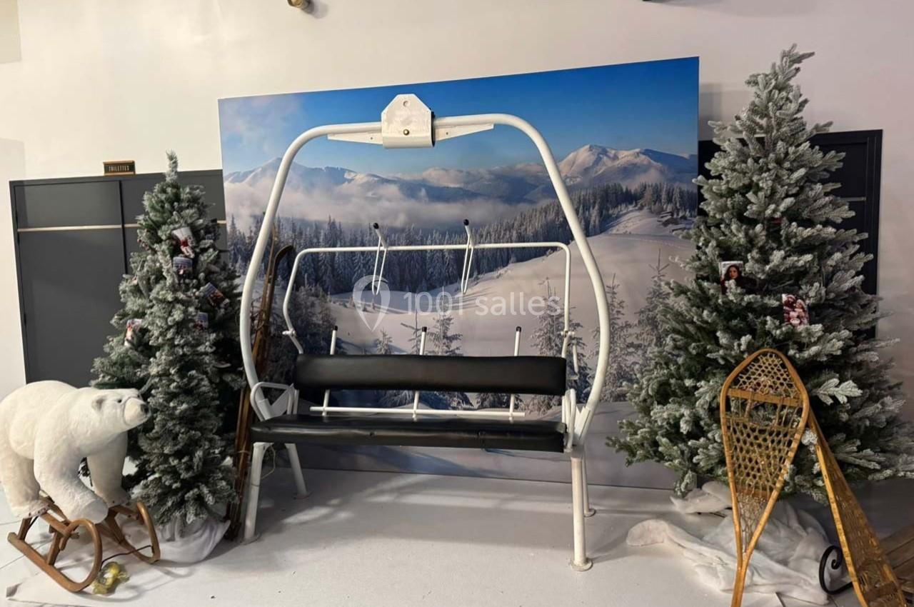 Banc en forme de télésiège entouré de sapins enneigés, d'une raquette et d'une décoration d'ours polaire.