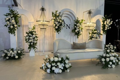 Voiture ancienne blanche stationnée devant une véranda moderne, entourée de végétation et d'arbres.