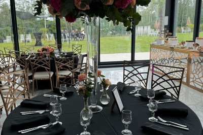 Voiture ancienne blanche stationnée devant une véranda moderne, entourée de végétation et d'arbres.
