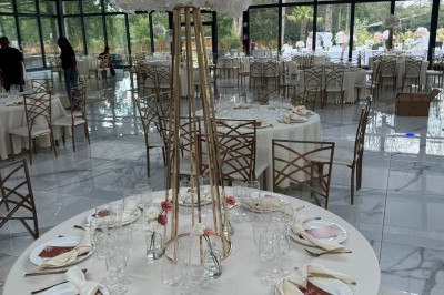 Voiture ancienne blanche stationnée devant une véranda moderne, entourée de végétation et d'arbres.