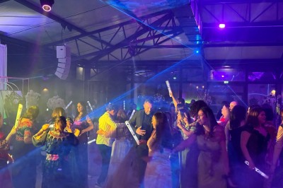 Voiture ancienne blanche stationnée devant une véranda moderne, entourée de végétation et d'arbres.