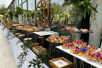 Voiture ancienne blanche stationnée devant une véranda moderne, entourée de végétation et d'arbres.