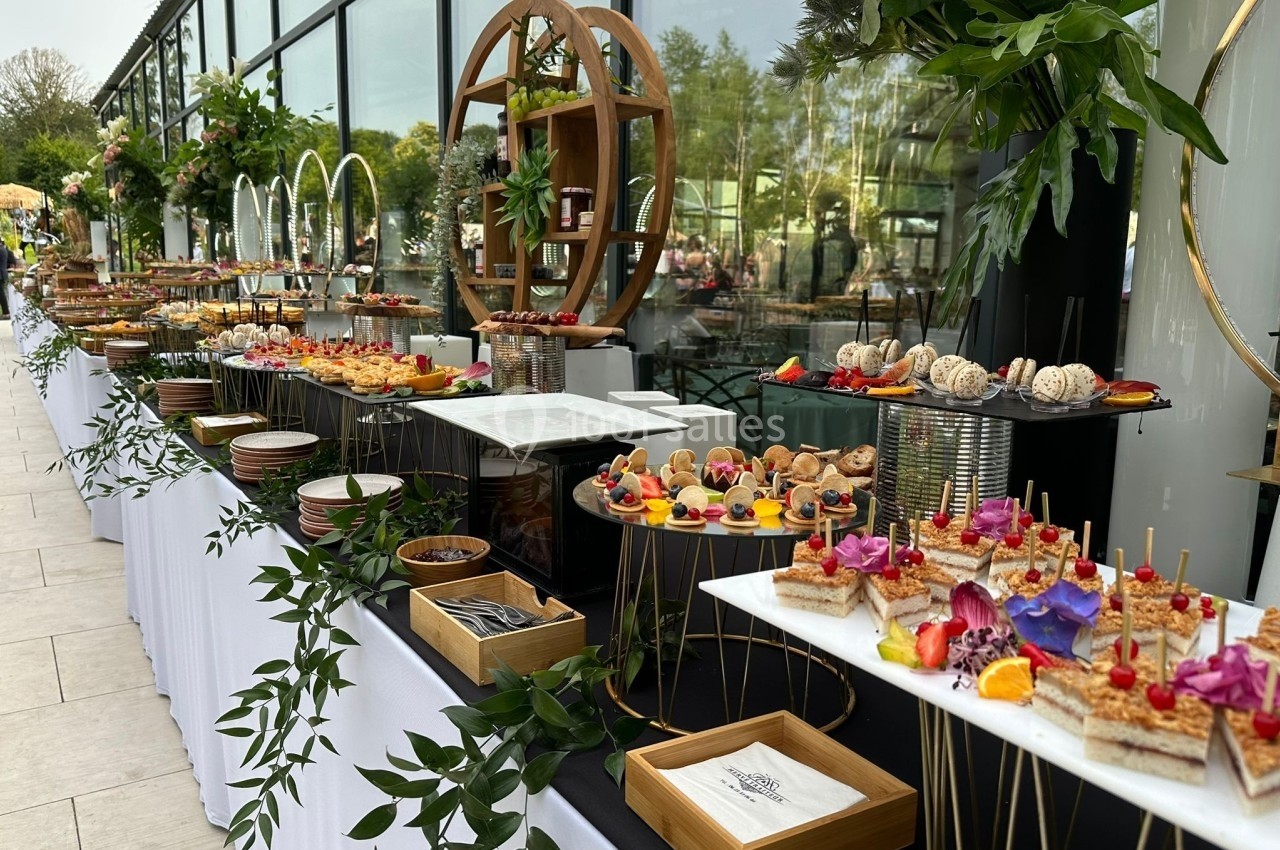 Buffet élégant en extérieur avec une variété de plats et desserts présentés sur des tables décorées de feuillages.