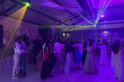 Voiture ancienne blanche stationnée devant une véranda moderne, entourée de végétation et d'arbres.