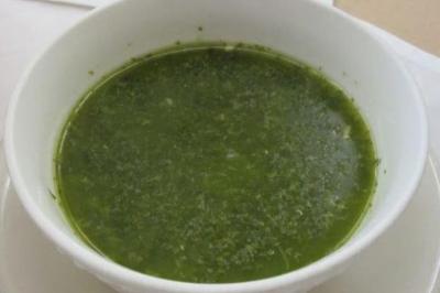 Plat de feuilles de légumes mijotées dans une sauce épicée, présenté dans une assiette blanche.