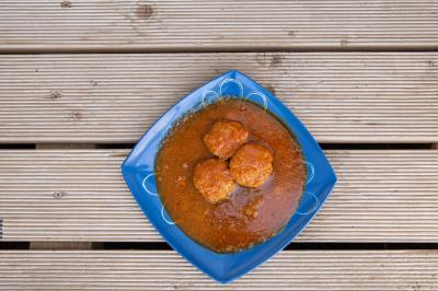Plat de feuilles de légumes mijotées dans une sauce épicée, présenté dans une assiette blanche.