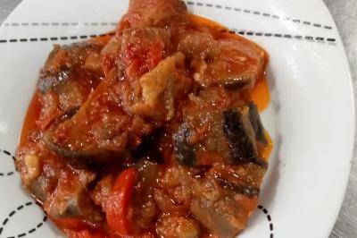 Plat de feuilles de légumes mijotées dans une sauce épicée, présenté dans une assiette blanche.