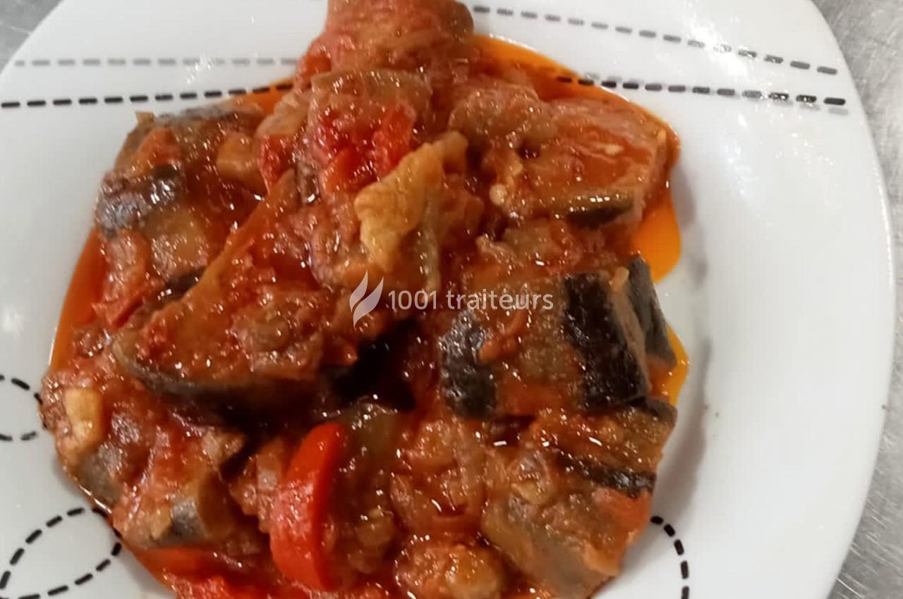 Plat de poisson en sauce tomate avec morceaux de légumes, servi sur une assiette blanche.