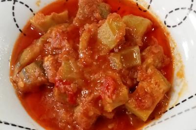 Plat de feuilles de légumes mijotées dans une sauce épicée, présenté dans une assiette blanche.