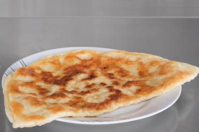 Galette dorée et croustillante servie sur une assiette blanche posée sur une surface métallique.