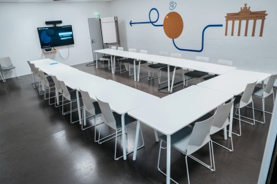 Miniature Location salle Lille (Nord) - B'twin Village #8 Salle de réunion moderne avec tables disposées en U, chaises noires et écrans interactifs sur les murs.