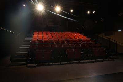 Salle de réunion lumineuse avec tables blanches, chaises orange et un tableau blanc sur pied.