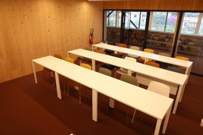 Salle de réunion lumineuse avec tables blanches, chaises orange et un tableau blanc sur pied.