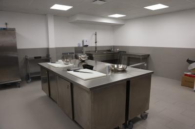 Salle de réunion lumineuse avec tables blanches, chaises orange et un tableau blanc sur pied.