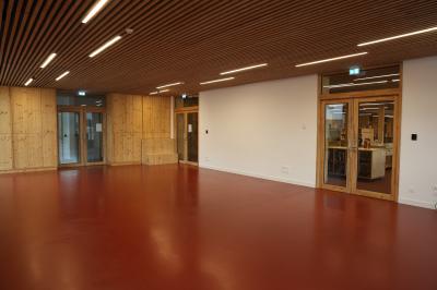 Salle de réunion lumineuse avec tables blanches, chaises orange et un tableau blanc sur pied.