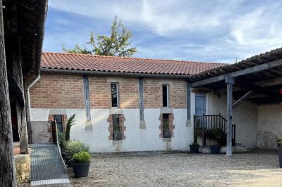 Salle rustique avec murs en pierre, poutres apparentes, table dressée, chaises en bois et coin salon avec canapé.