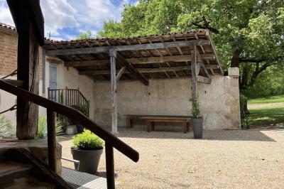 Salle rustique avec murs en pierre, poutres apparentes, table dressée, chaises en bois et coin salon avec canapé.