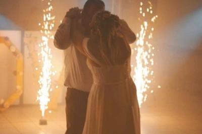 Des couples dansent sous des jeux de lumière colorés dans une salle sombre, créant une ambiance festive.