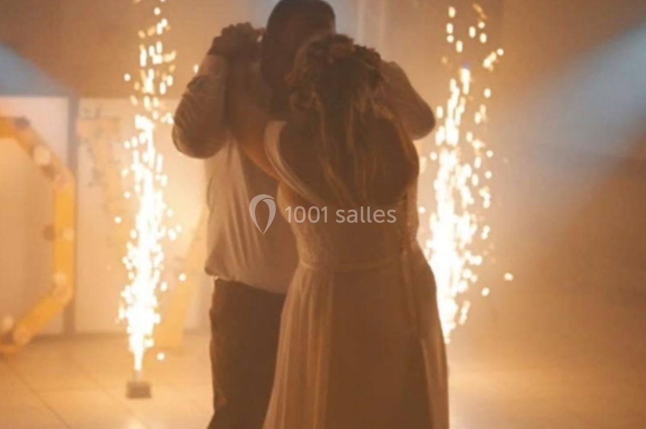 Un couple danse sous des lumières tamisées avec des étincelles en arrière-plan dans une ambiance festive.