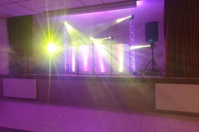 Des couples dansent sous des jeux de lumière colorés dans une salle sombre, créant une ambiance festive.