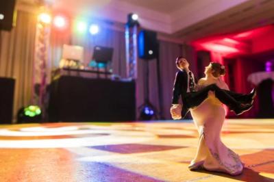 Des couples dansent sous des jeux de lumière colorés dans une salle sombre, créant une ambiance festive.