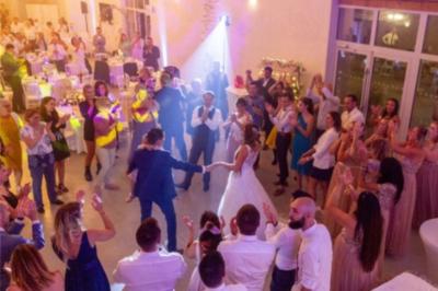 Des couples dansent sous des jeux de lumière colorés dans une salle sombre, créant une ambiance festive.