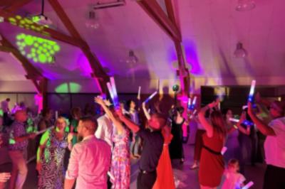 Des couples dansent sous des jeux de lumière colorés dans une salle sombre, créant une ambiance festive.