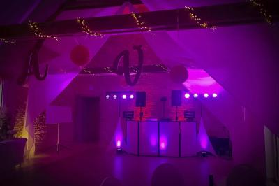 Des couples dansent sous des jeux de lumière colorés dans une salle sombre, créant une ambiance festive.