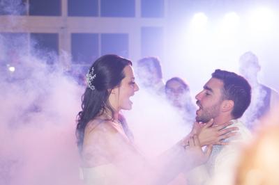 Des couples dansent sous des jeux de lumière colorés dans une salle sombre, créant une ambiance festive.