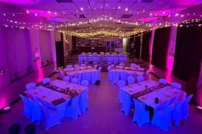 Des couples dansent sous des jeux de lumière colorés dans une salle sombre, créant une ambiance festive.
