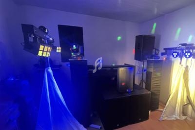 Installation de matériel de sonorisation et d'éclairage dans une pièce, avec projecteurs colorés et enceintes.