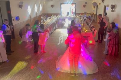 Salle décorée pour une réception, avec des invités dansant et discutant autour de tables illuminées.