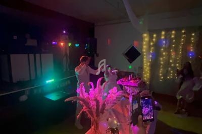 Deux personnes dansent sous des lumières colorées dans une salle décorée avec des guirlandes lumineuses et des fleurs.