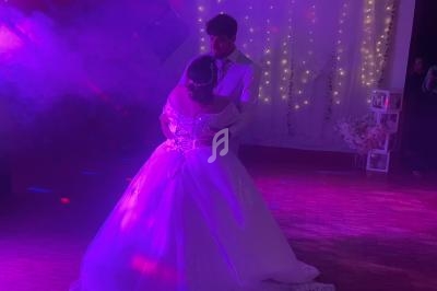 Un couple danse sous des lumières colorées dans une ambiance festive, entouré de décorations lumineuses.