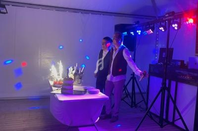 Deux personnes debout près d'une table avec un gâteau d'anniversaire illuminé par des bougies étincelantes, dans une…