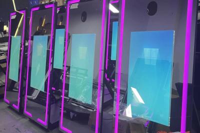 Deux femmes souriantes se tiennent près d'une borne photo dans un espace intérieur avec des tables et des chaises en arrière…