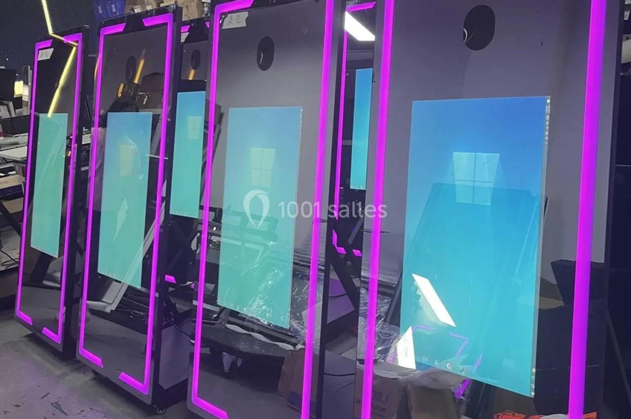 Quatre écrans verticaux avec cadres lumineux roses alignés dans un environnement industriel.