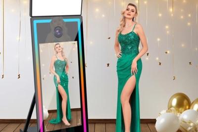 Deux femmes souriantes se tiennent près d'une borne photo dans un espace intérieur avec des tables et des chaises en arrière…