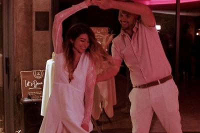 Un couple danse joyeusement dans une ambiance tamisée avec des lumières rouges en arrière-plan.