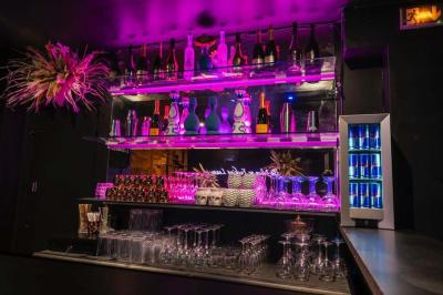 Bar élégant avec comptoir géométrique, étagères illuminées de bouteilles, tabourets bas et ambiance tamisée.