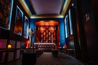 Bar élégant avec comptoir géométrique, étagères illuminées de bouteilles, tabourets bas et ambiance tamisée.