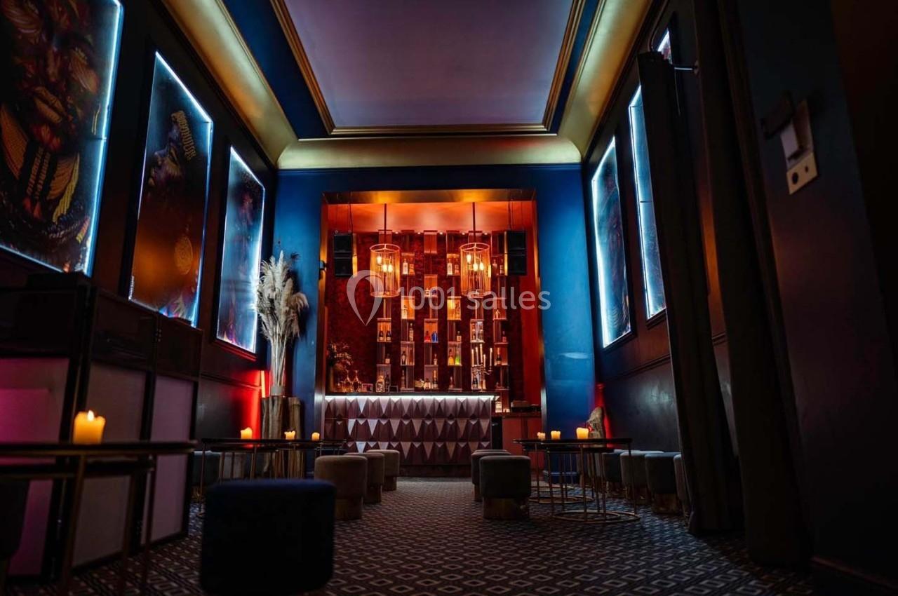 Bar élégant avec éclairage tamisé, décor moderne, tabourets bas et bougies créant une ambiance chaleureuse.