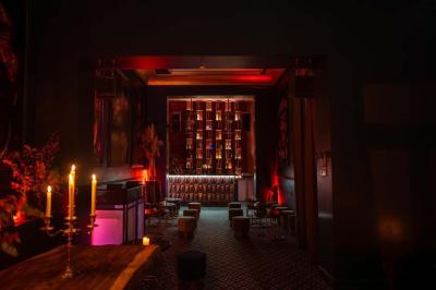 Bar élégant avec comptoir géométrique, étagères illuminées de bouteilles, tabourets bas et ambiance tamisée.