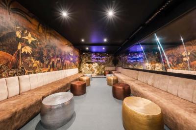 Bar élégant avec comptoir géométrique, étagères illuminées de bouteilles, tabourets bas et ambiance tamisée.