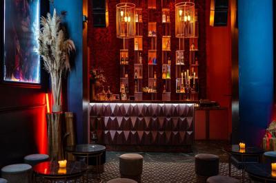 Bar élégant avec comptoir géométrique, étagères illuminées de bouteilles, tabourets bas et ambiance tamisée.