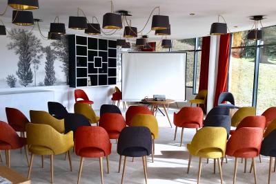 Salle de réunion lumineuse avec tables disposées en U, chaises jaunes, écran de projection et tableau blanc.